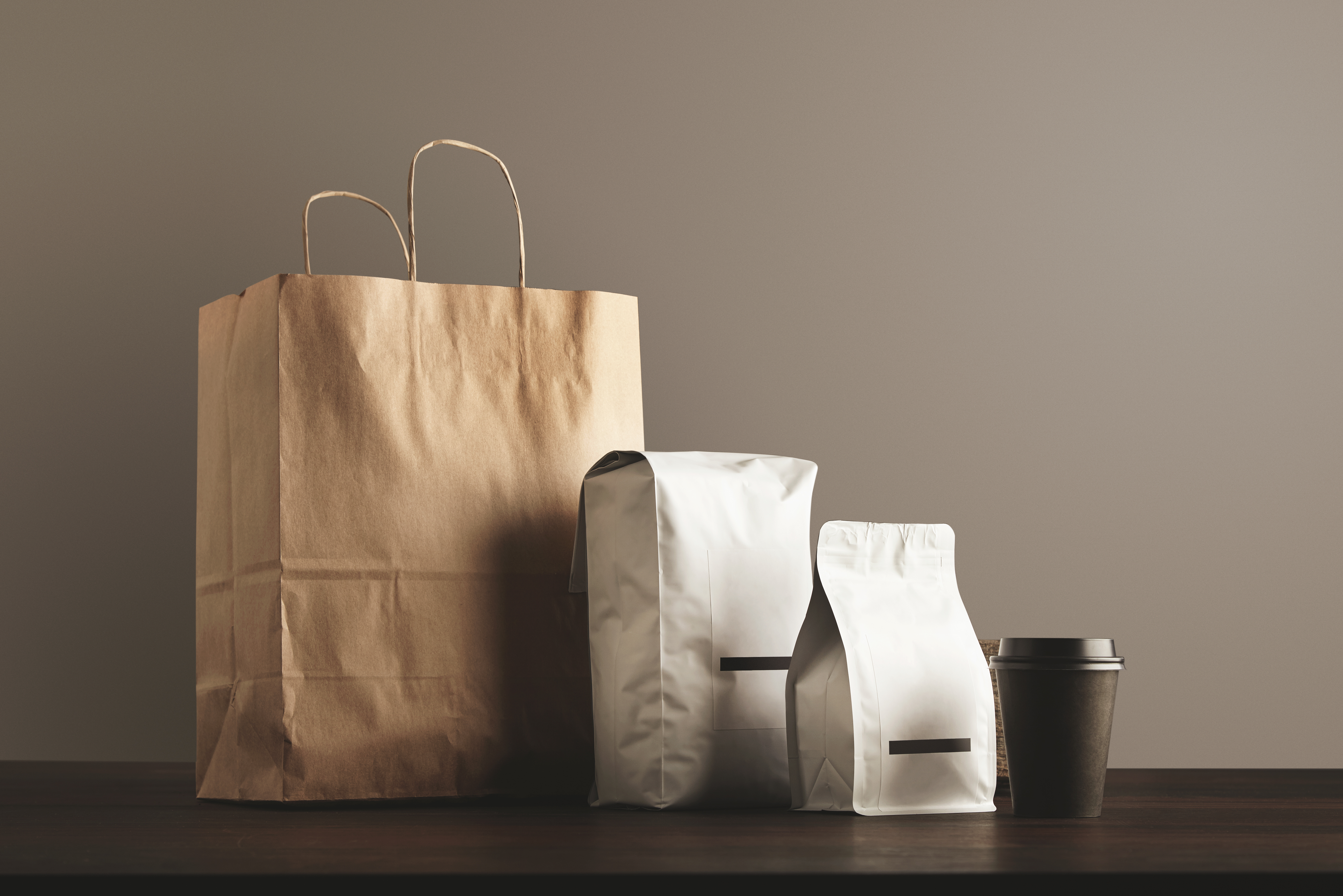 Presentation of retailer package set: craft paper bag, big pouch, small container and take away glass with cap. Filled with goods, blank labeled, merchandisepack